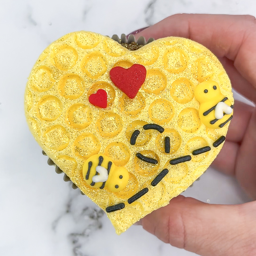 Bee Mine Cupcakes with yellow buttercream honeycomb, red heart sprinkles, and bumblebee decorations.