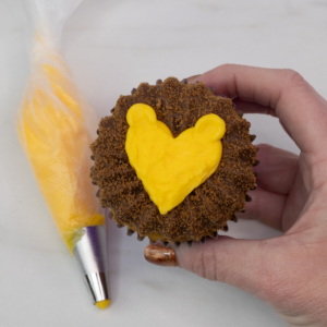 Adding yellow buttercream ears to the fuzzy lion. Step 7.