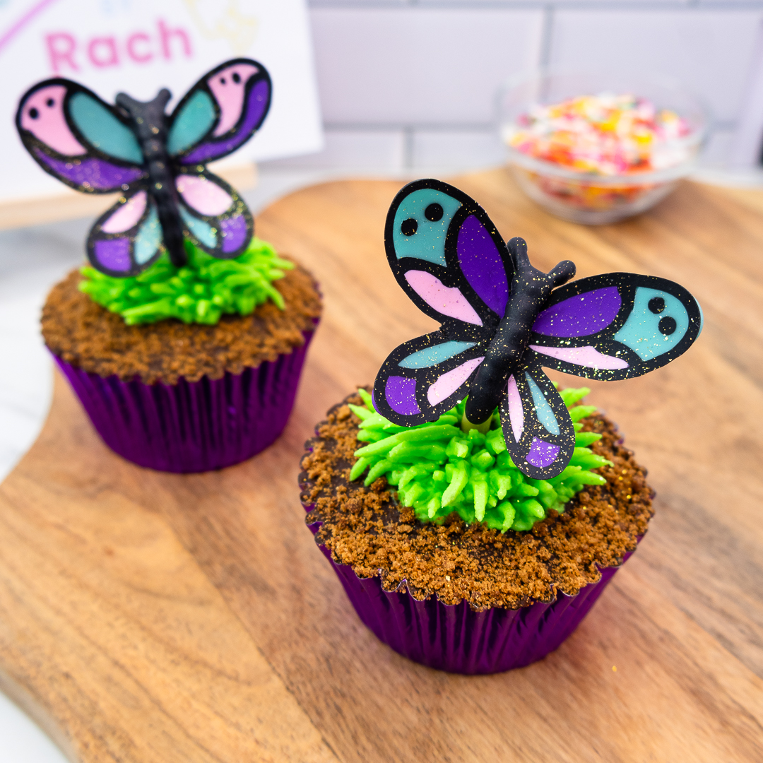 Bright butterfly cupcakes displayed on a wooden board
