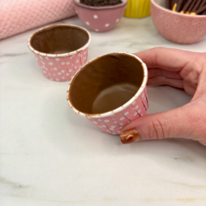 Second layer of chocolate candy melts spooned into cupcake liners to form edible wrappers