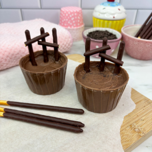 Adding chocolate pocky sticks to form fences around cupcakes