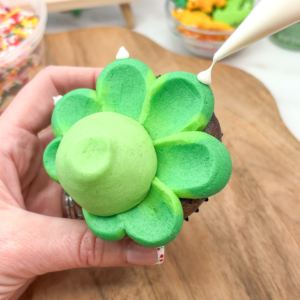 Adding small candy melt horns to dinosaur cupcake. Step 7.