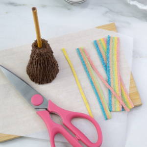 Cutting rainbow sour straps into thin strips for the broomstick ties.