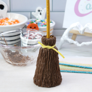 Wrapping a yellow sour strap around the chocolate broomstick to create the band.