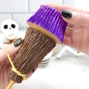 Pressing a chocolate cupcake with buttercream onto the open end of the broomstick.