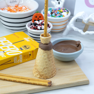 Inserting a Pepero stick into the top of the broom to make the handle.