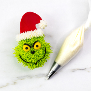 Finished Grinch cupcake with Santa hat, buttercream hat trim and bright green piped fur