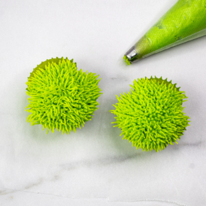 Two green grinch cupcakes with piping bag