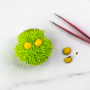 Grinch cupcake with yellow candy eyes and tweezers