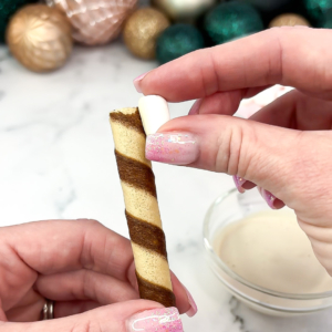 Attaching a mini marshmallow to one end of a wafer stick to make a bone shape.