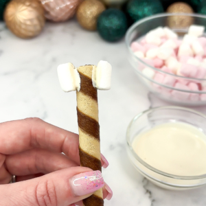Attaching mini marshmallows to each end of a wafer stick to make a bone shape.