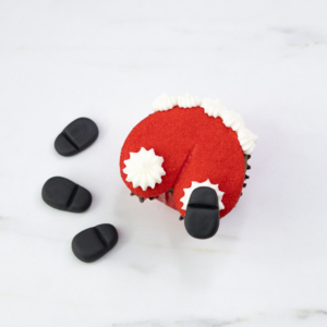 Santa butt cupcake with black fondant boots being placed on either side of the shaped dip to complete the design.