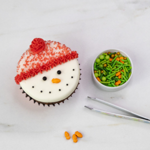Adding the carrot nose to the snowman cupcake with orange buttercream for a 3D effect.