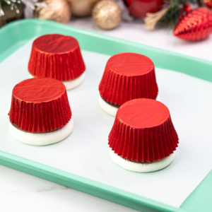 Pressed and frozen cupcake tops ready for decorating snowman faces in this simple Christmas cupcake design.