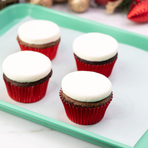 Four cupcakes flipped and frozen to create the flat snowman face foundation for decorating
