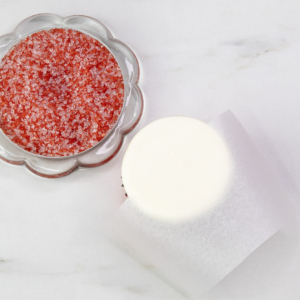 A bowl of red sanding sugar ready to be used for the snowman’s winter hat in this Christmas cupcake tutorial.