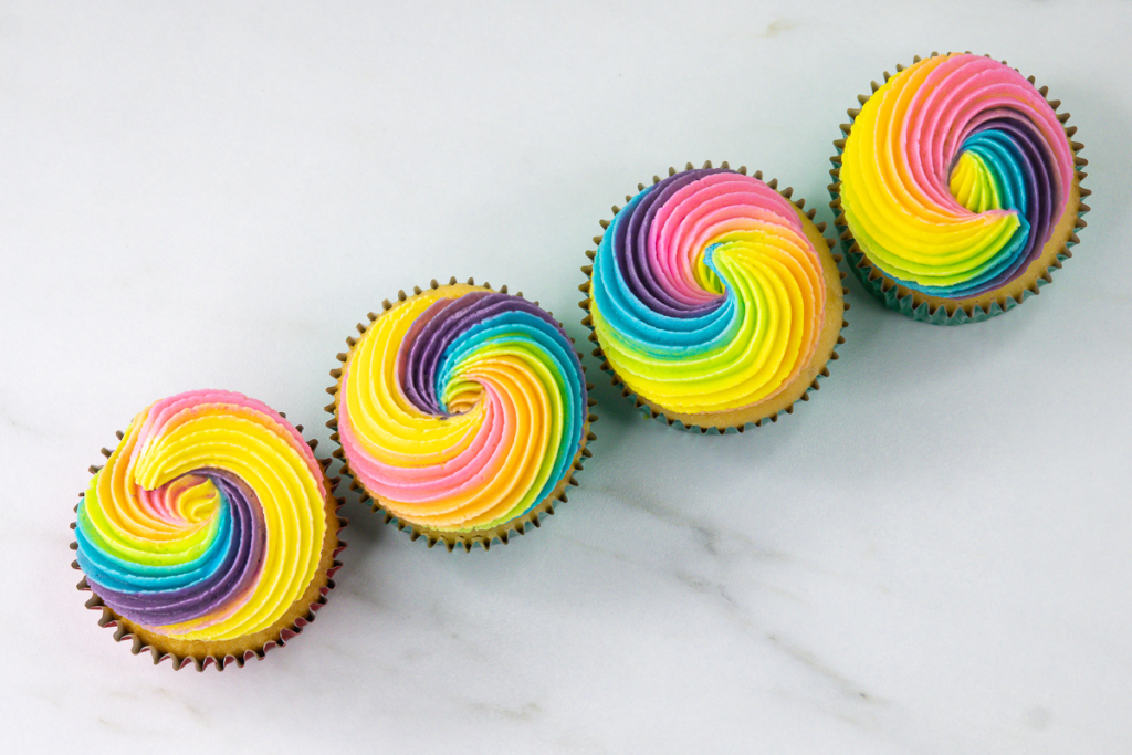 Rainbow swirl cupcakes decorated with pastel pink, peach, yellow, green, blue and purple buttercream.