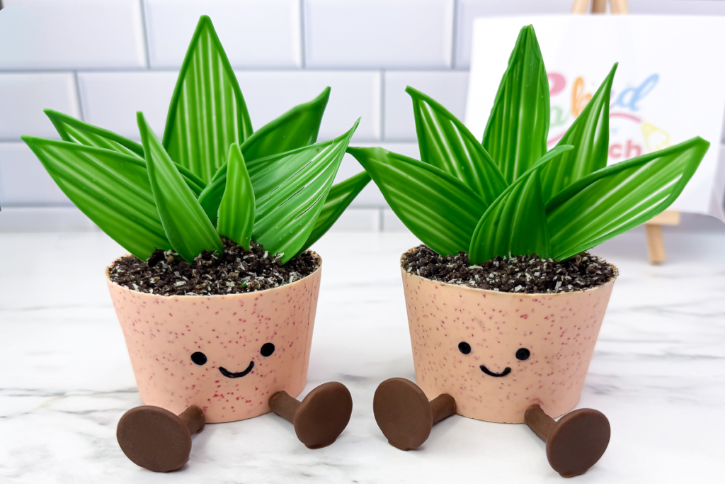 Two easy chocolate plant pot cupcakes decorated with handmade chocolate leaves, Oreo soil and cute smiling flower pots.